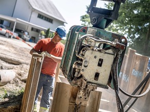 Mit einem Anbauvibrator werden die Spundwände in den Boden vibriert.