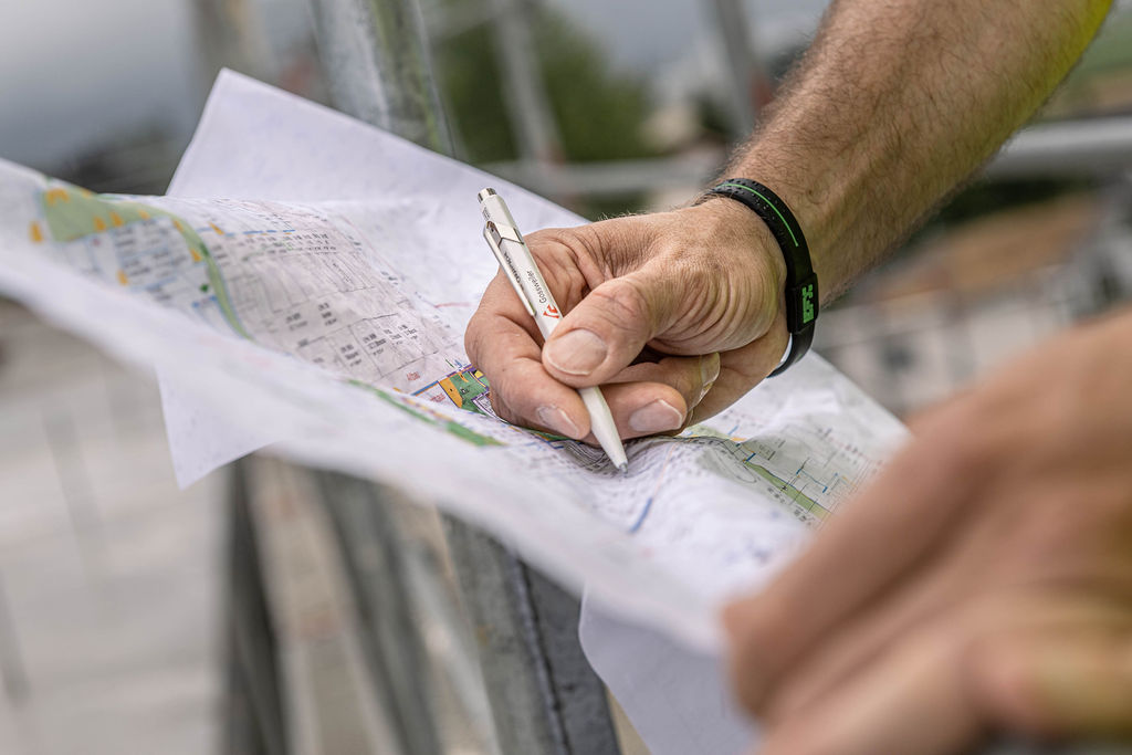 Mitarbeiter zeigt mit Gossweiler-Stift auf ein Detail eines Planes